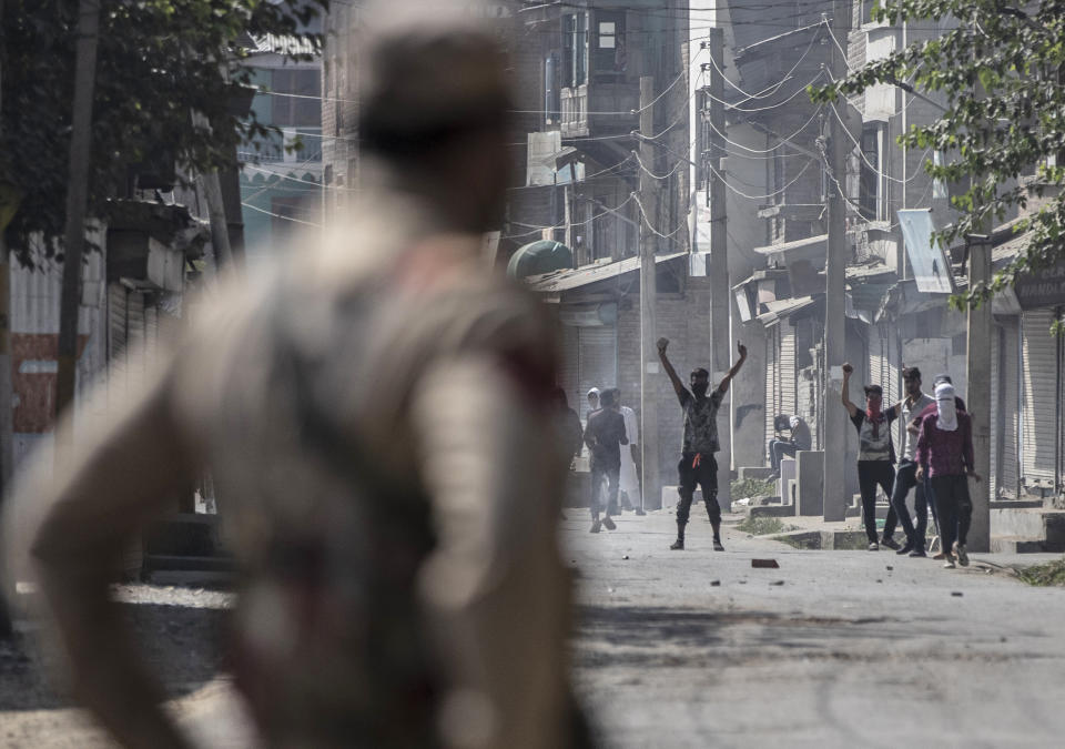 A Kashmiri man shouts freedom slogans as a police officer looks from a distance after a gun battle in Srinagar, Indian controlled Kashmir, Thursday, Sept. 17, 2020. The gunfight erupted shortly after scores of counterinsurgency police and soldiers launched an operation based on a tip about the presence of militants in a Srinagar neighborhood, Pankaj Singh, an Indian paramilitary spokesman, said. (AP Photo/Mukhtar Khan)