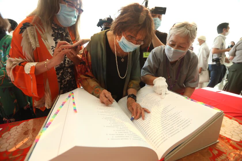 LOS ANGELES, CA - SEPTEMBER 24, 2022 - - June Aochi Berk, 90, places a "hanko" a special seal to mark the names of her parents in the sacred book Ireicho, a new national monument with125,000 names of Japanese Americans who interned at 75 relocation camps during World War II, at the Japanese American National Museum in Los Angeles on September 24, 2022. Her daughter Susan Yamashiro, left, watched on. Berk interned at Santa Anita and Rohwer camps during World War II with her family. (Genaro Molina / Los Angeles Times)