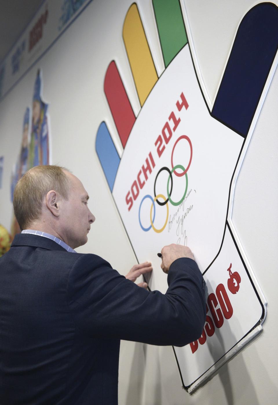 Russian President Vladimir Putin signs a wall during his visit to an Olympic volunteer's centre in Sochi