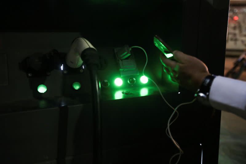 A man charges his cell phone at an electric vehicle charging station in Mexico City