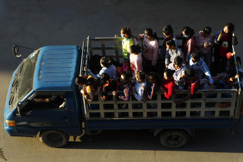 FILE - In this Aug. 26, 2020, file photo, Cambodian garment factory workers ride on the back of a truck as they head to work outside Phnom Penh, Cambodia. The coronavirus pandemic has slammed the apparel industry, leaving many of the 65 million Asian garment factory workers struggling as factories close or cut back on wages, and the International Labor Organization is urging the industry to do more to protect them. (AP Photo/Heng Sinith, File)