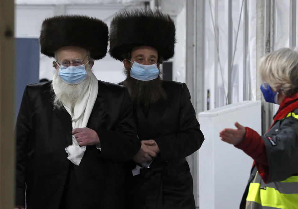 FILE - In this Saturday, Feb. 13, 2021 file photo, two men from the Haredi Orthodox Jewish community arrive at an event to encourage vaccine uptake in Britain's Haredi community at the John Scott Vaccination Centre in London. Thanks to an efficient vaccine roll out program and high uptake rates, Britain is finally saying goodbye to months of tough lockdown restrictions. From Monday May 17, 2021, all restaurants and bars can fully reopen, as can hotels, cinemas, theatres and museums, and for the first time since March 2020, Britons can hug friends and family and meet up inside other people’s houses. (AP Photo/Frank Augstein, File)