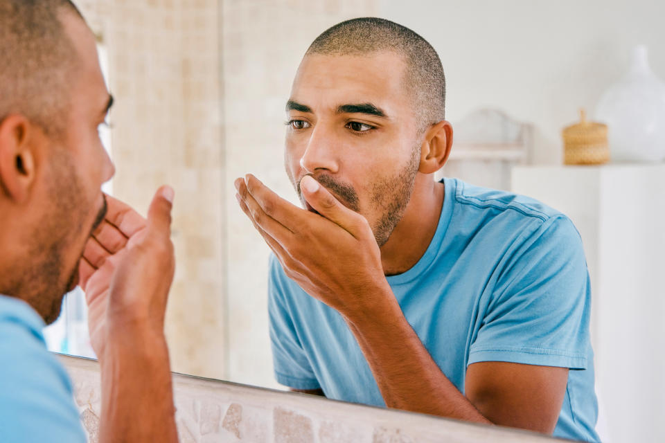 A man checks his breath in the mirror - bad breath was named as one of the biggest icks people have in a new survey