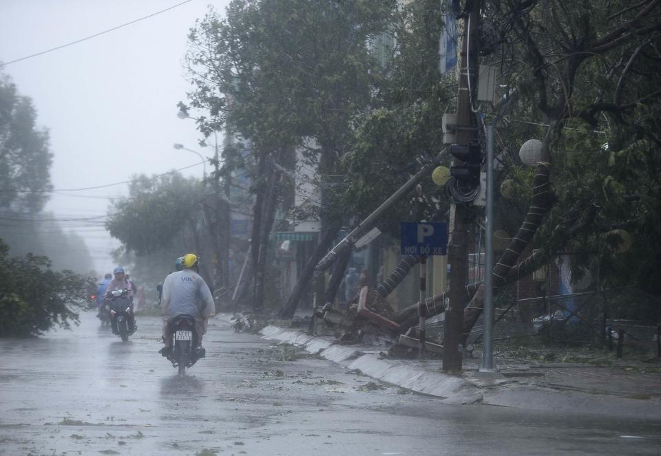 Motorcyclists ride past along fallen trees, caused by Typhoon Nari, along a street in Vietnam's central Danang city, October 15, 2013. Typhoon Nari knocked down trees and damaged hundreds of houses in central Vietnam early on Tuesday, forcing the evacuation of tens of thousands of people, state media said. More than 122,000 people had been moved to safe ground in several provinces, including Quang Nam and Danang city, by late Monday before the typhoon arrived, the official Tuoi Tre (Youth) newspaper reported. (REUTERS/Duc Hien)