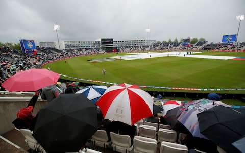 Frustrated spectators cower under umbrellas as play in South Africa v West Indies in the Cricket World Cup is stopped by rain   - Credit: Andrew Boyers/Reuters