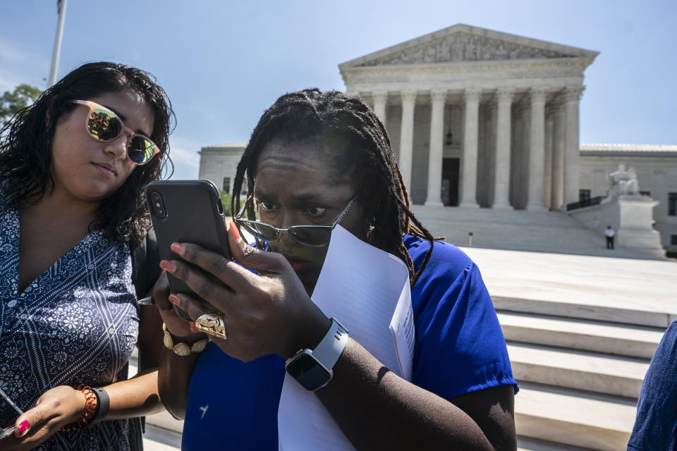 Nana Gyamfi, center, executive director of the Black Alliance for Just Immigration, watches her cell phone for news as the Supreme Court put a hold on the Trump administration's effort to add a citizenship question to the 2020 census, on Capitol Hill in Washington, Thursday, June 27, 2019. (AP Photo/J. Scott Applewhite)