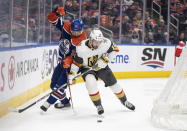 Vegas Golden Knights' Nicolas Roy (10) and Edmonton Oilers' Darnell Nurse (25) compete for the puck during the third period of an NHL hockey game Saturday, March 25, 2023, in Edmonton, Alberta. (Jason Franson/The Canadian Press via AP)