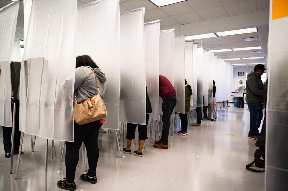 Residents of Cuyahoga county, separated by plastic due to health concerns amid the coronavirus pandemic, fill out paper ballots for early, in-person voting at the board of elections office in downtown Cleveland, Ohio, on Oct. 16, 2020.