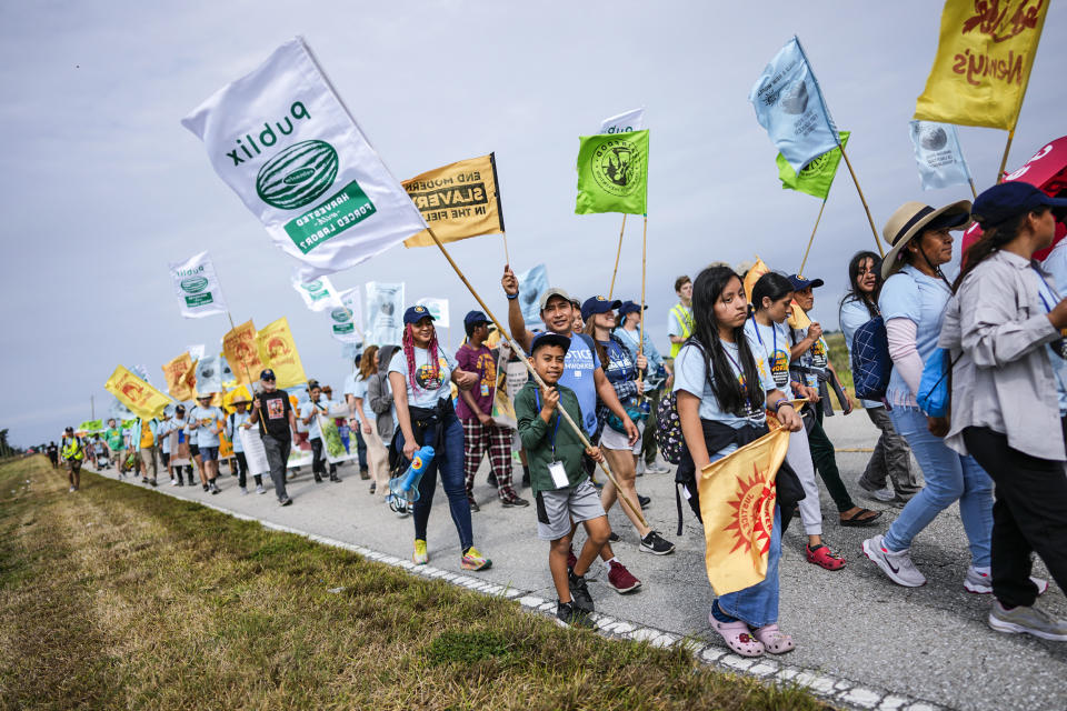 Image: Gelder Perez, 10, center, carries a protest flag as he walks with his uncle Leonel Perez, center right, on the first day of a five-day trek aimed at highlighting the Fair Food Program, in an effort to pressure retailers to leverage their purchasing power to improve conditions for farmworkers, on March 14, 2023, in Pahokee, Fla. (Rebecca Blackwell / AP)