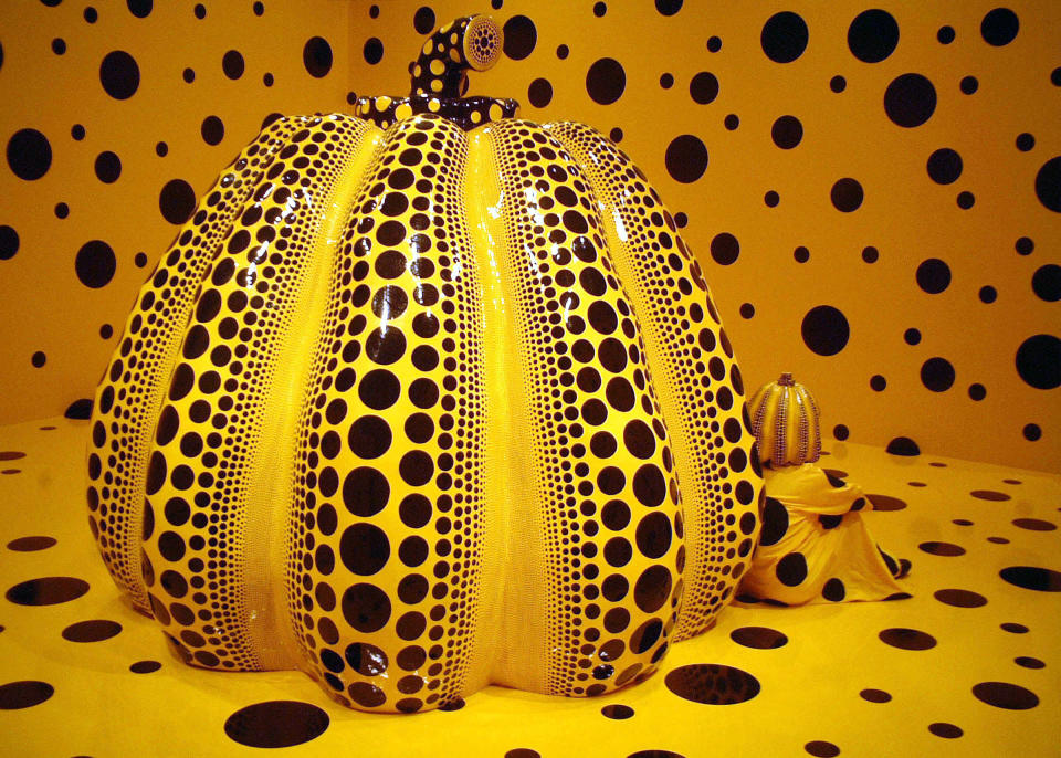 In this undated photo released by Yayoi Kusama Studio Inc., photo, Japanese artist Yayoi Kusama sits by her 1998 Pumpkin, a collection of Iwami Art Museum, Shimane, Japan, in an installation at Matsumoto City Museum of Art in Matsumoto, central Japan. Kusama's signature splash of dots has now arrived in the realm of fashion in a new collection from French luxury brand Louis Vuitton - bags, sunglasses, shoes and coats. The latest Kusama collection is showcased at its boutiques around the world, including New York, Paris, Tokyo and Singapore, sometimes with replica dolls of Kusama. (AP Photo/Yayoi Kusama Studio Inc.) NO SALES, EDITORIAL USE ONLY, CREDIT MANDATORY