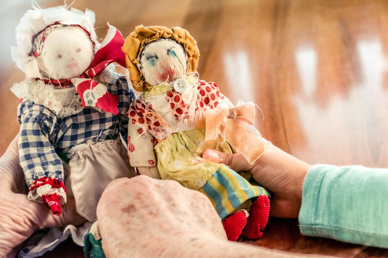 senior woman hands holding old homemade sewn dolls