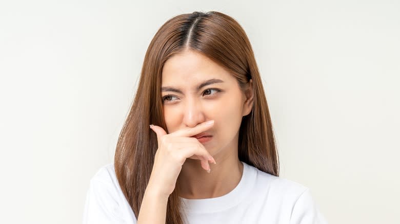 woman pinching nose from smell