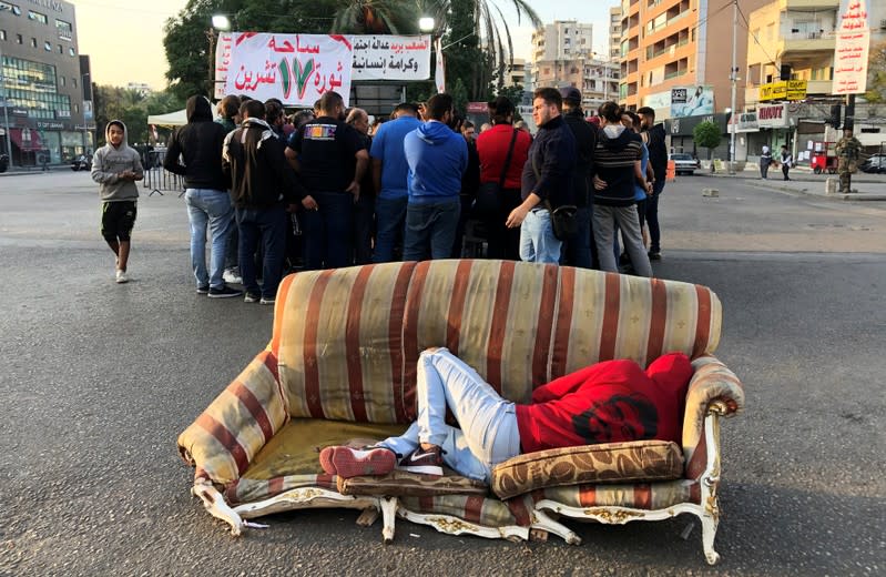 A demonstrator lies on a sofa along a street during ongoing anti-government protests, in the southern city of Sidon