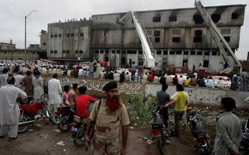 People gather at the site of burnt garment factory in Baldia Town, Karachi, Pakistan on Wednesday, Sept. 12, 2012. Pakistani officials say the death toll from devastating factory fires that broke out in two major cities has risen to 128. Hospital official Tariq Kaleem said the fire at a garment factory in the southern Pakistani city of Karachi killed 103 people. A blaze at a shoe factory in the eastern city of Lahore killed 25 people. (AP Photo/Fareed Khan) - AP Photo/Fareed Khan