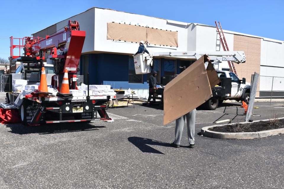 A construction worker carries a massive sheet of cardboard over his head in Berlin Township, where workers are converting a former Arby's into a Sonic restaurant and a Buffalo Wild Wings Go.