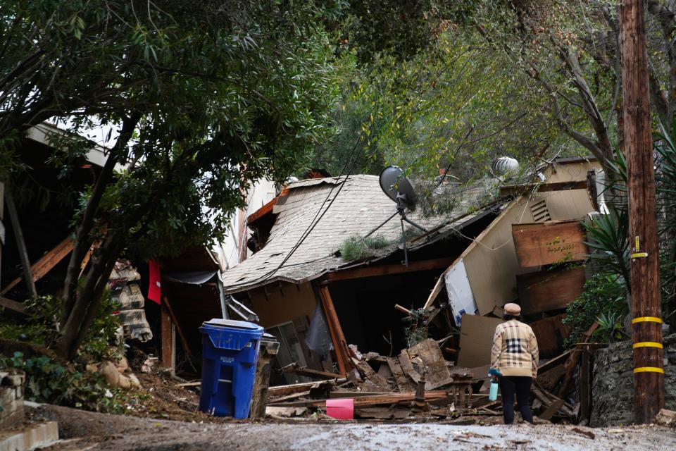 A local resident checks the damage to her neighbor's house after heavy rains and mud flows caused it to slide down from the hill in Beverly Glen (Copyright 2024 The Associated Press. All rights reserved.)