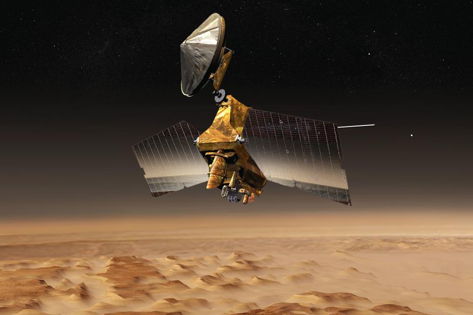 This illustration made available by NASA depicts the Mars Reconnaissance Orbiter mission over the red planet. On Thursday, Oct. 27, 2022, NASA announced two of their spacecraft, one on the surface and the other in orbit,. have recorded the biggest meteor strikes and impact craters yet. (NASA/JPL-Caltech via AP)