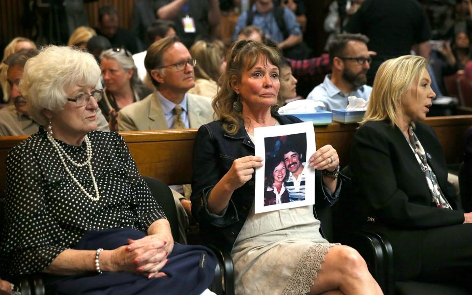 An attendee holds a photo of Cheri Domingo and her boyfriend Gregory Sanchez, who were killed in 1981, as she sits in the courtroom during the arraignment of Joseph James DeAngelo, the suspected "Golden State Killer" on April 27, 2018 in Sacramento, California - Getty