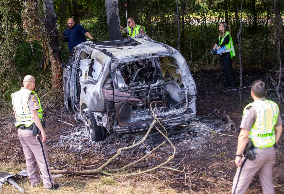 Medical Examiner Investigator Kyle Jones, top left, works with Florida Highway Patrol Trooper Cpl. Justin Bard, center, and Morgue Technician Emily Johnson, right, at the scene of a fiery crash on Wednesday morning near the Irvine/McIntosh exit on Interstate 75. Two people died in the crash and three people were hospitalized.