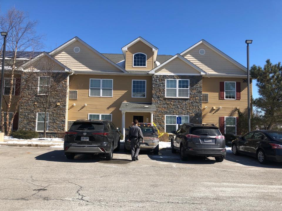 A state police trooper walks toward a car stationed outside an apartment building at The Views at Rocky Glen complex Monday.