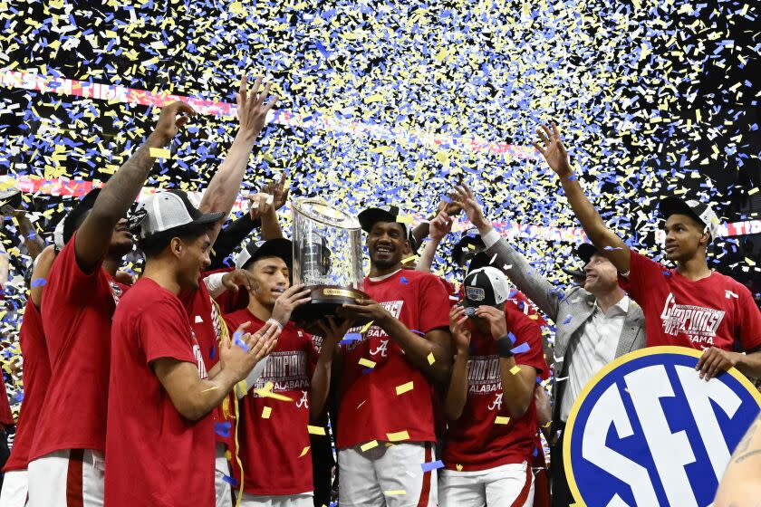 Alabama players pose with the trophy after an NCAA college basketball game against Texas A&M.