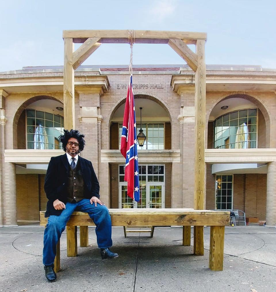 Sarasota artist John Sims sits on his provocative art installation "The Proper Way to Hang a Confederate Flag" outside Scripps Hall at the Kennedy Museum of Art at Ohio University.