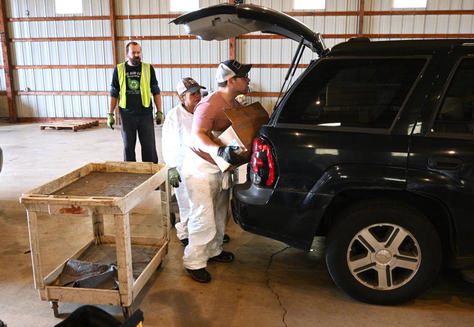 Employees of DLD, Inc unload hazardous materials from an SUV brought to the Saturday BBPU annual collection.
