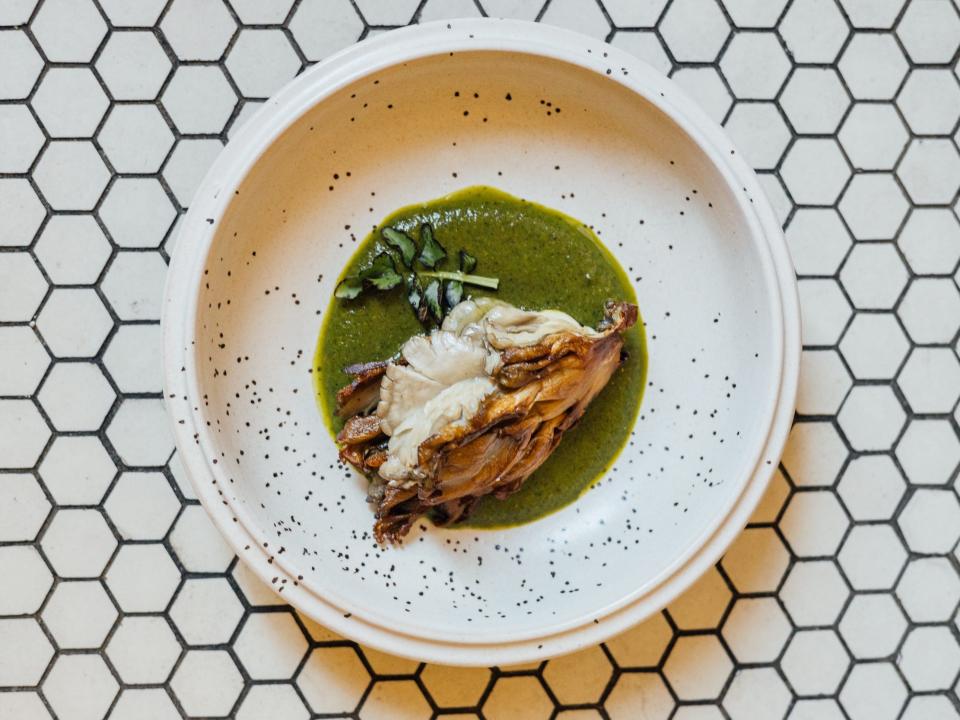 A plate of mushrooms, charred green tomatoes, chile, and lime.