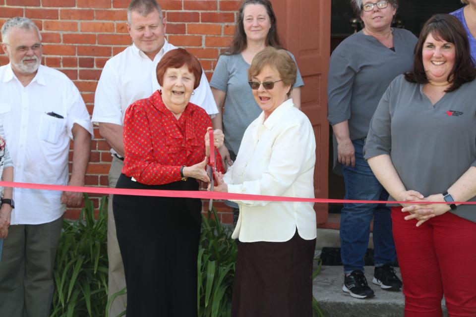 Marion County Historical Society volunteers Jan Augenstein and Carol Robinson, center, prepare to cut the ribbon to officially reopen Linn School on Thursday, May 12, 2022. Augenstein and Robinson both conduct programming at Linn School, showing school children what life was like in a one-room schoolhouse.