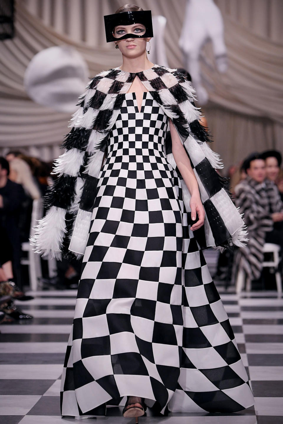 <p>Ein Model trägt bei der Dior Frühjahr/Sommer 18 Haute Couture Modenschau ein schwarz-weiß-kariertes, gefiedertes Cape und ein dazu passendes Kleid. (Bild: Getty Images) </p>