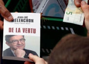 A supporter buys a book as Jean-Luc Melenchon of the French far left Parti de Gauche and candidate for the 2017 French presidential election holds a political rally in Toulouse, Southwestern France, April 16, 2017. REUTERS/Regis Duvignau