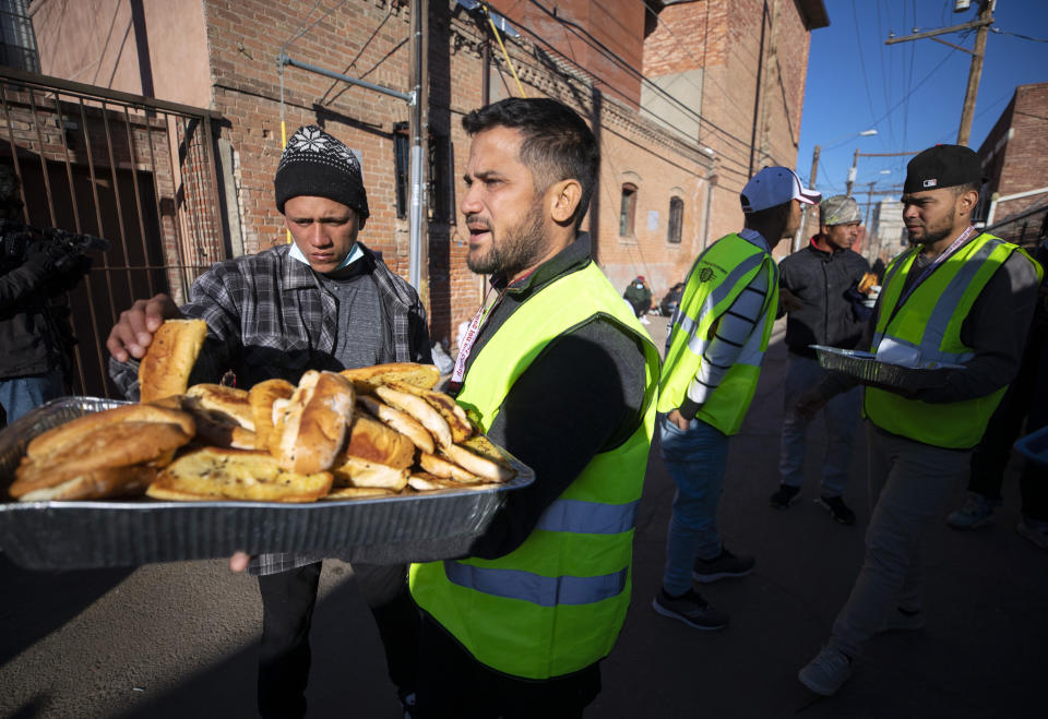 FILE - Church volunteers serve garlic bread to migrants camping outside the Sacred Heart Church in downtown El Paso, Texas, Sunday, Jan. 8, 2023. (AP Photo/Andres Leighton, File)