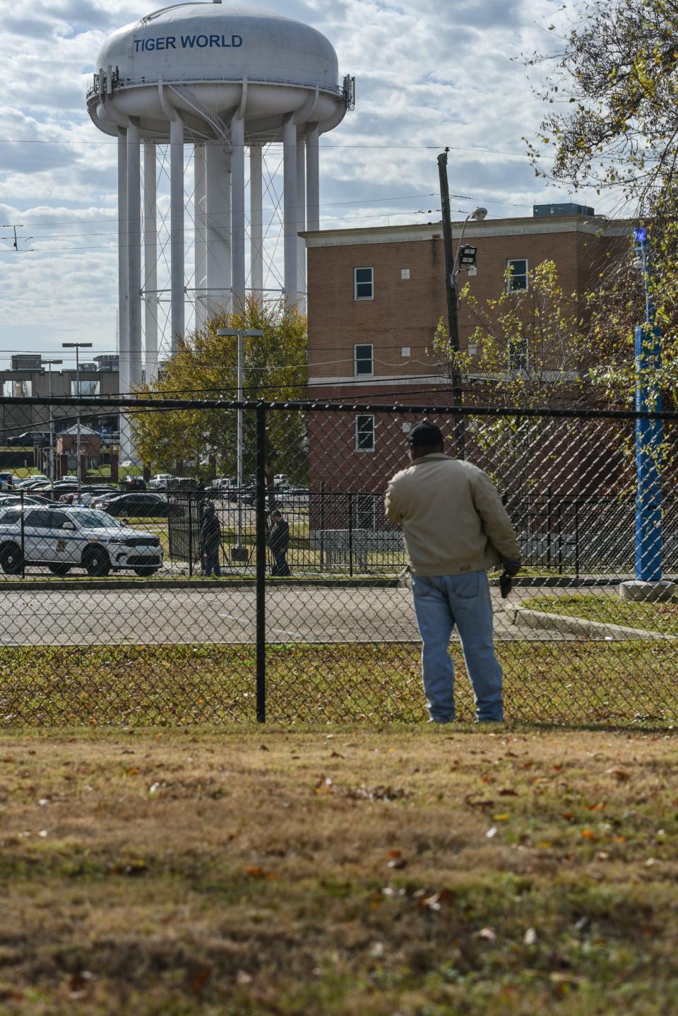 A passerby stops to investigate as officials from the Hinds County Coroner's Department load a body into a Coroner's vehicle near Dixon Hall on the Jackson State campus in Jackson, Miss., Friday, December 2, 2022. Officials from the Hinds County Coroner's Department, Hinds County Sheriff's Office, Mississippi Bureau of Investigations and Jackson State President, Thomas. Hudson, were all identified at the scene of the incident.