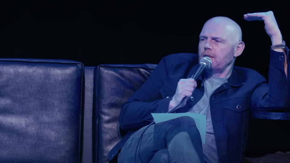 Bill Burr sitting on a couch, telling a joke at one of his shows.