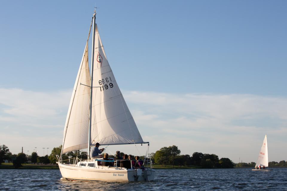 Joshua Harsch's pocket cruiser vessel, named Blue Heaven, carries passengers around Lake Shawnee while a smaller vessel sails in the distance recently for the explore sailing lessons through the county and Shawnee Yacht Club.