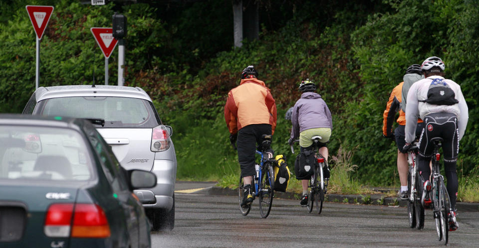 In this May 31, 2012 photo, bicyclists commute during the morning rush hour past cars in Seattle. For many in Seattle, the image of a typical cyclist is a Spandex-clad, yellow-jacketed two-wheeled warrior who braves the steep streets of this city. But as the city prepares to overhaul its five-year-old bike plan, some are seeking to make the city safer and friendlier to those not so accustomed to navigating the streets on two wheels. There's a new push to get “willing but wary” cyclists on their saddles with protected bike lanes buffered from traffic, designated bicycling boulevards where traffic is slowed and walkers and bikers have priority, and traffic calming features like speed bumps. (AP Photo/Elaine Thompson)