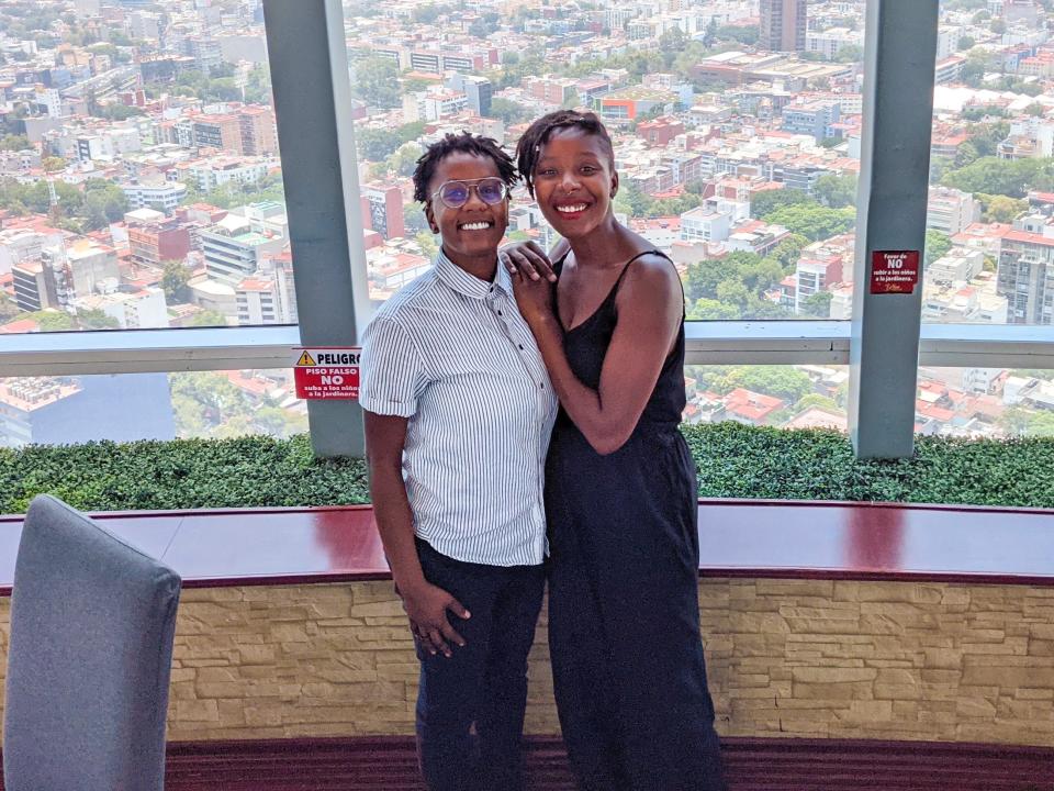 Amber and her partner posing in front of an impressive aerial building view