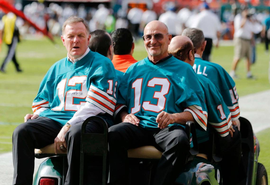 FILE - In this Dec. 16, 2012, file photo, Bob Griese (12) and Jake Scott (13), of the 1972 Miami Dolphins, are driven onto the field for a halftime celebration during the Dolphins’ NFL football game against the Jacksonville Jaguars in Miami. Scott, the star safety who was the most valuable player in the Super Bowl that completed the Dolphins’ 1972 perfect season, died Thursday, Nov. 19, 2020, in Atlanta. He was 75. Scott died after a fall down a stairway that left him in a coma, former teammate Dick Anderson said. (AP Photo/John Bazemore, File)
