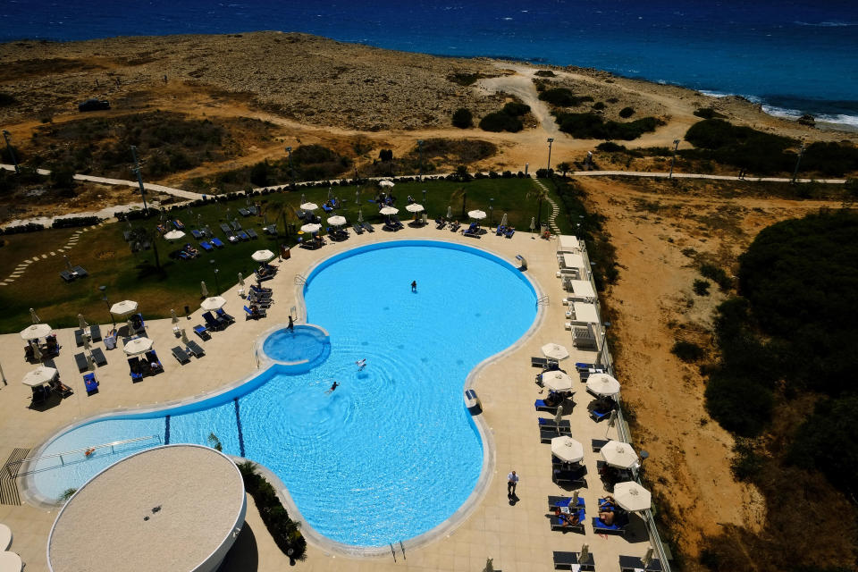 People enjoy their vacations at the pool of Nissi Blue hotel in southeast resort of Ayia Napa, in the eastern Mediterranean island of Cyprus, Saturday, May 22, 2021. Cypriot hotel and other tourism-related business owners say they'd like to see the COVID-19 pandemic-induced uncertainty over travel bookings to the tourism-reliant island nation winding down by July when they're hoping authorities in Cyprus' main markets including the U.K., Russia, Germany and the Scandinavian countries will make it easier for their citizens to travel abroad. (AP Photo/Petros Karadjias)