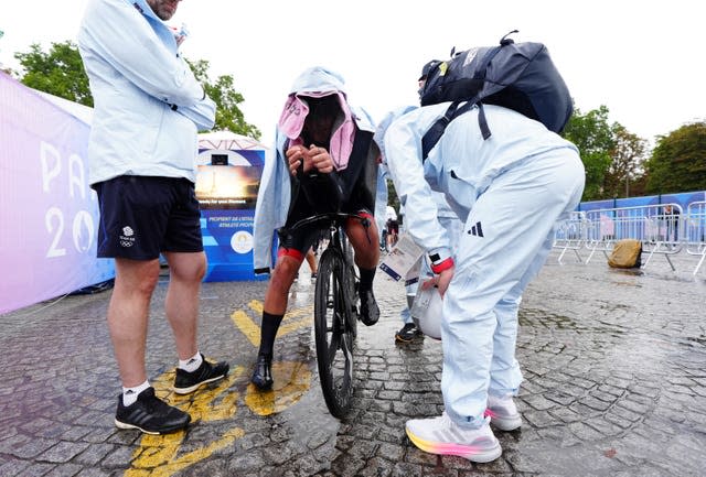 Josh Tarling with his head covered and sat on his bike at the end of the time trial after missing out on a medal.