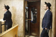 An Israeli police officer wearing protective gear waits behind a door to detain ultra-Orthodox men as they pray in a synagogue because of the government's measures to help stop the spread of the coronavirus, in Bnei Brak, a suburb of Tel Aviv, Israel, April 2, 2020. ‏On Wednesday, Israeli Prime Minister Benjamin Netanyahu ordered a police cordon around the largely ultra-Orthodox city of Bnei Brak, to limit movement to and from the city. Bnei Brak has the second highest number of coronavirus cases in Israel. (AP Photo/Ariel Schalit)