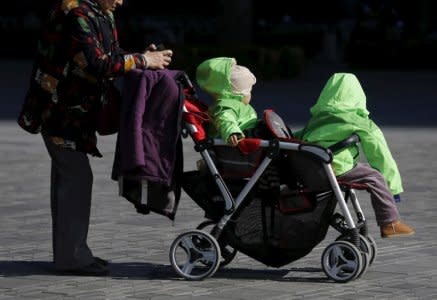 FILE PHOTO: An elderly woman pushes two babies in a stroller in Beijing, China October 30, 2015. REUTERS/Kim Kyung-Hoon/File Photo