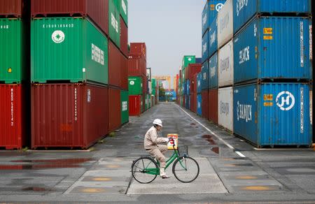 FILE PHOTO: A worker rides a bicycle in a container area at a port in Tokyo April 21, 2014. REUTERS/Toru Hanai/File Photo