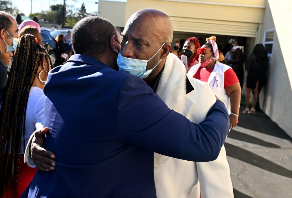 Activist Najee Ali comforts Tioni Theus' father, during a funeral.