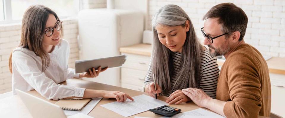 Insurance agent consulting couple, pointing at something on a page in front of them.