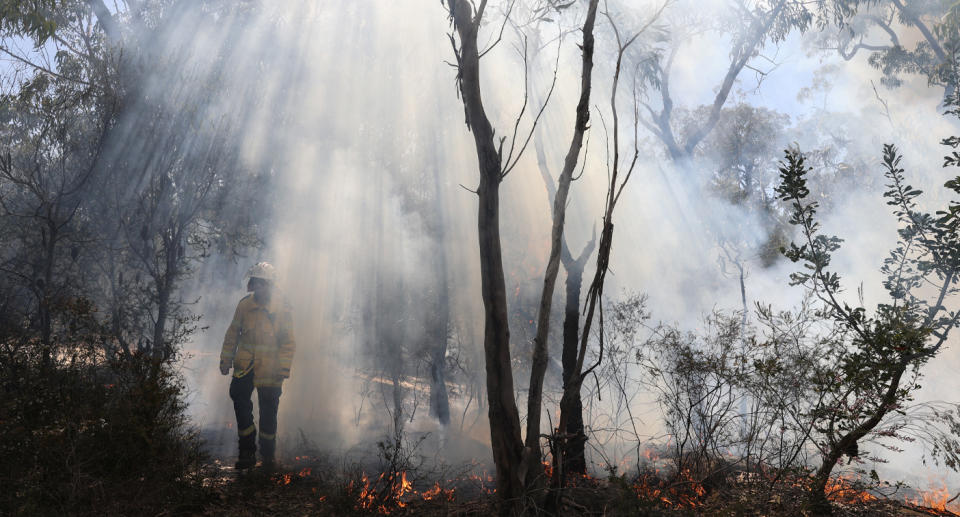 Firefighter emerging from smouldering fire.