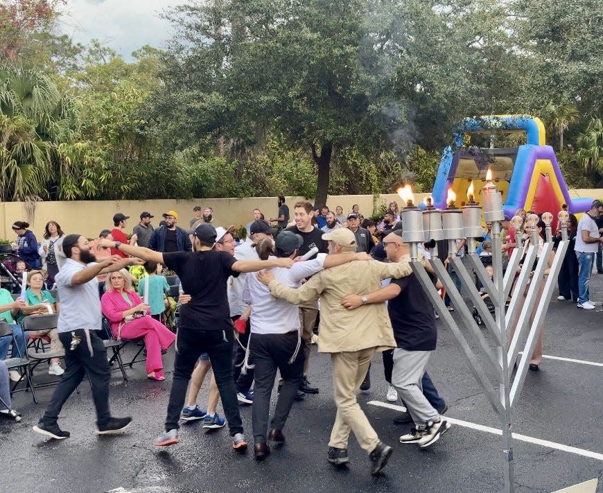Members of the synagogue Chabad Lubavitch of Greater Daytona Beach dance for joy after the menorah is lit on the fourth day of Hanukkah on Sunday.