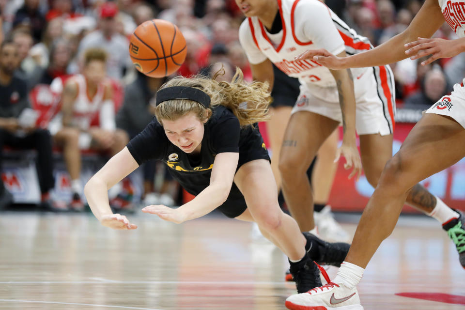 Iowa guard Molly Davis, left, is knocked down as Ohio State guard Hevynne Bristow, back right, defends on the play during the first half of an NCAA college basketball game at Value City Arena in Columbus, Ohio, Monday, Jan. 23, 2023. (AP Photo/Joe Maiorana)