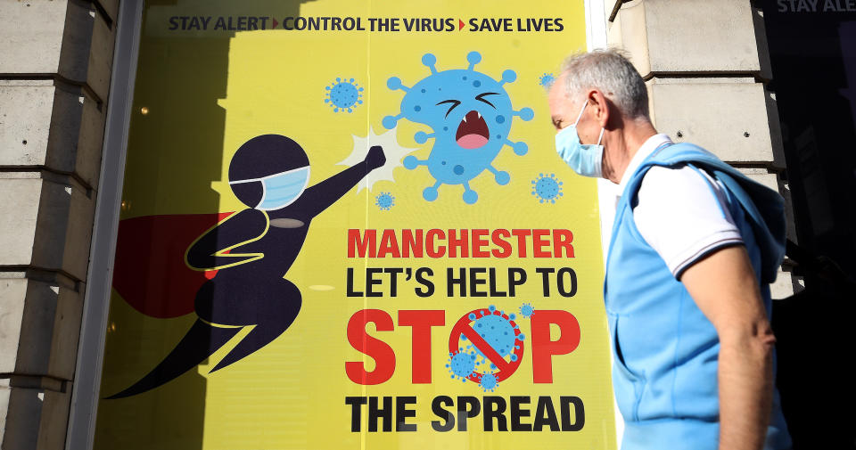 A person wearing a face mask walks past a Covid-19 sign on Deansgate in Manchester as the Government is preparing to impose stringent new coronavirus controls on 2.8 million people after talks with the local leaders for Greater Manchester failed to reach agreement. Leaders have been given until midday on Tuesday to reach a deal, or face unilateral Government action, after 10 days of negotiations failed to reach an agreement. (Photo by Martin Rickett/PA Images via Getty Images)