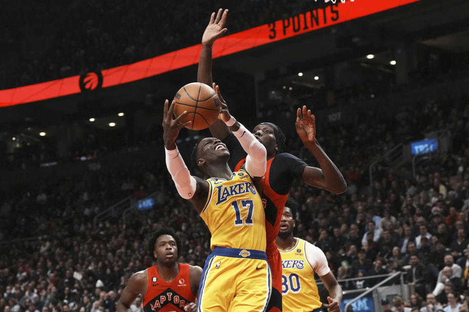 Los Angeles Lakers' Dennis Schroder (17) goes to the net as Toronto Raptors' Chris Boucher defends during first half of an NBA basketball game in Toronto on Wednesday, Dec. 7, 2022. (Chris Young/The Canadian Press via AP)